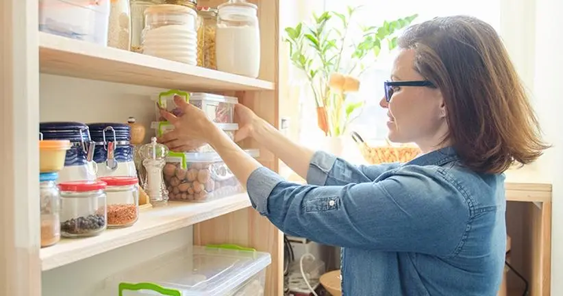 woman putting tupperwares on a pantry shelf